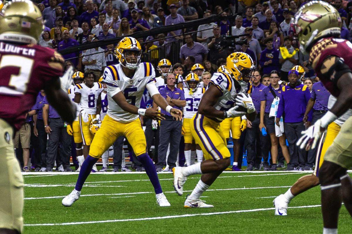 LSU football junior quarterback Jayden Daniels (5) gives the ball to junior running back Noah Cain (21) as head coach Brian Kelly watches on the sideline Sunday, Sept. 4, 2022, during LSU's Allstate Kickoff game defeat to Florida State 23-24 in the Caesars Superdome, New Orleans, La.