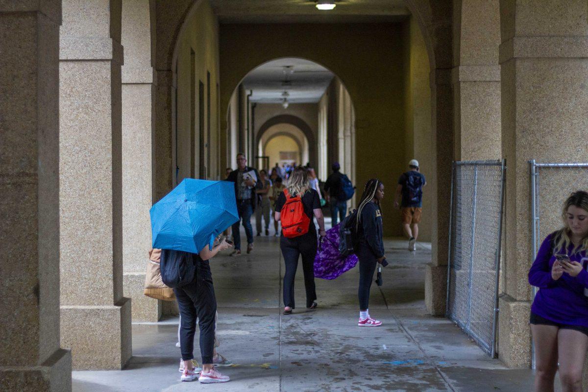 Students take shelter from the rain Tuesday, Sept. 26, 2023, under the colonnade in the LSU Quad in Baton Rouge, La.