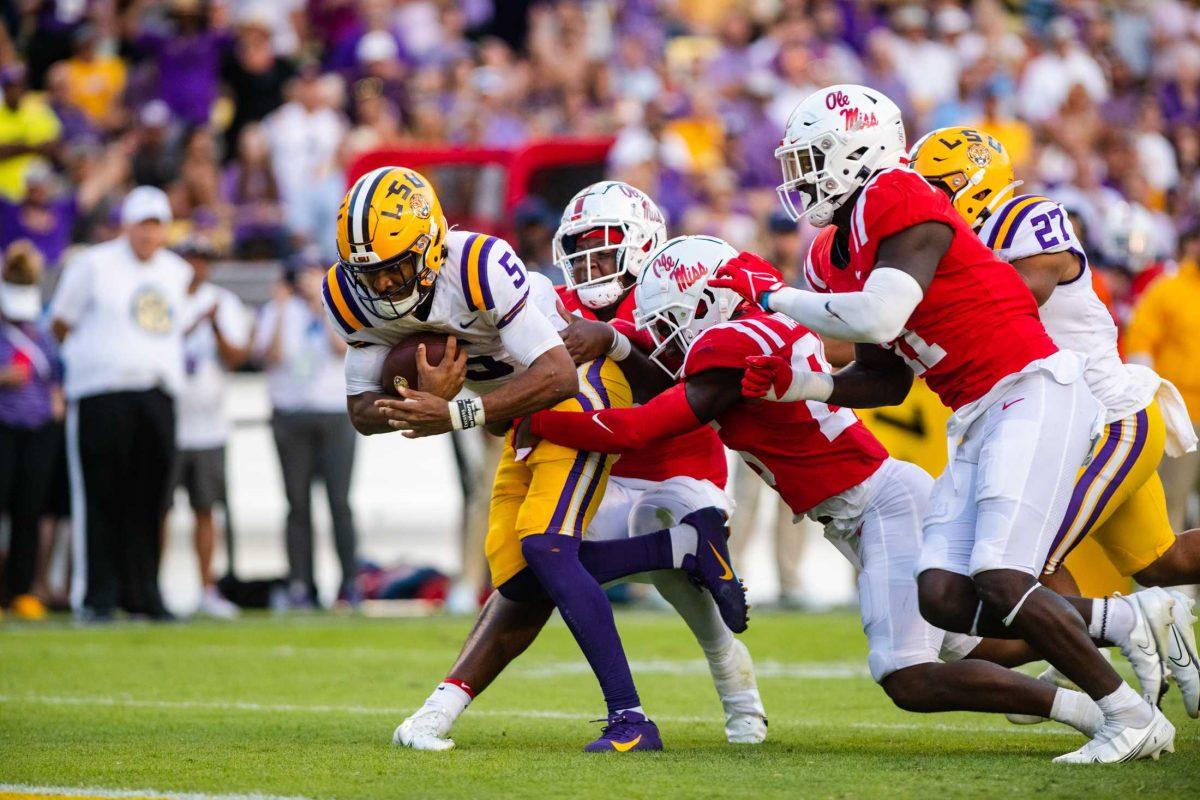 <p>LSU football junior quarterback Jayden Daniels (5) tries to get away from Ole Miss defensive players Saturday, Oct. 22, 2022, during LSU’s 45-20 win against Ole Miss at Tiger Stadium in Baton Rouge, La.</p>