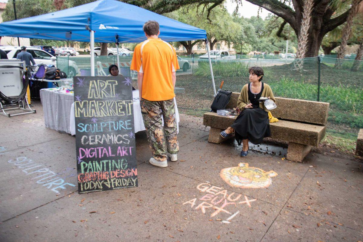 A student looks at art on display at the LSU art market hosted by the College of Art and Design on Thursday, Nov. 16, 2023, outside the LSU Student Union on Highland Road in Baton Rouge, La.