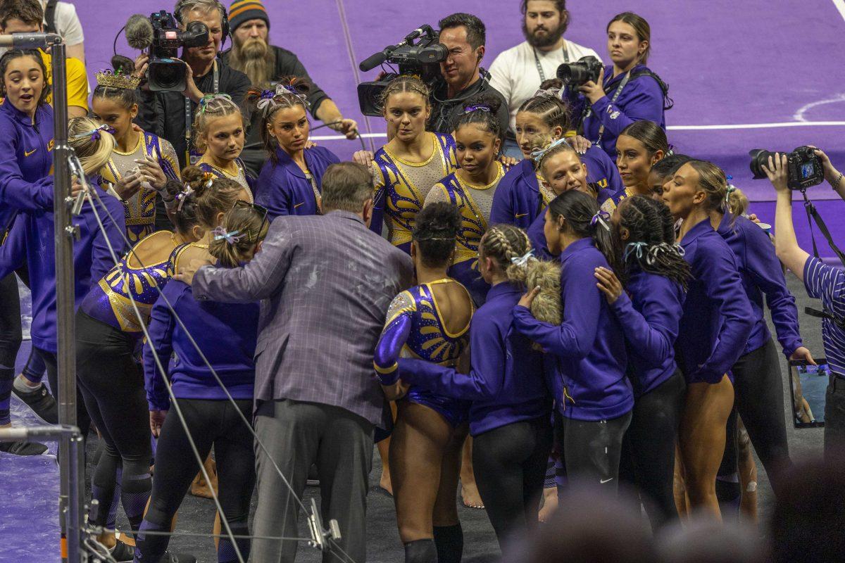 The LSU gymnastics team huddles up for some quick words from head coach Jay Clark Friday, Jan. 19, 2024, during LSU&#8216;s 198.125 - 197.600 victory over the University of Kentucky in the Pete Maravich Assembly Center.