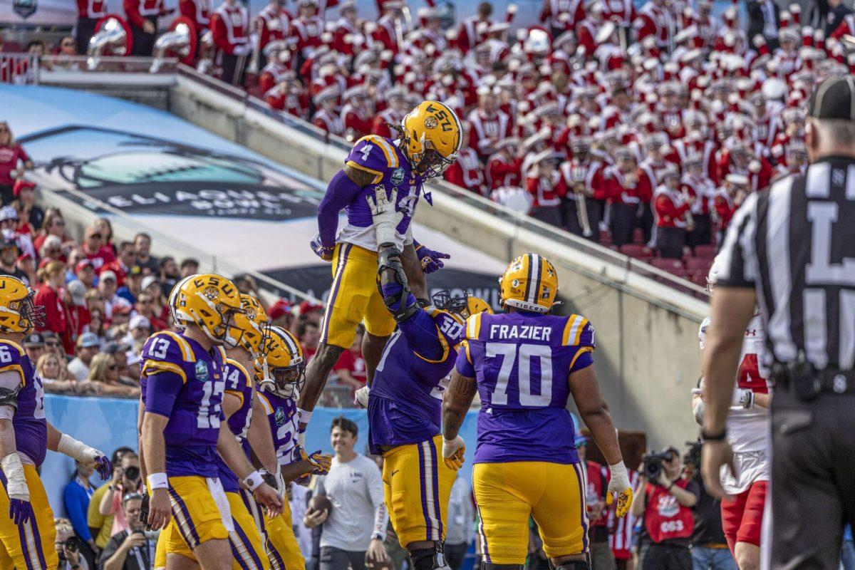 LSU football sophomore offensive lineman Emery Jones Jr. (50) lifts senior running back John Emery Jr. (4) after a touchdown Monday, Jan. 1, 2024, during LSU's 35-31 win over Wisconsin at the Raymond James Stadium in Tampa, Fl.