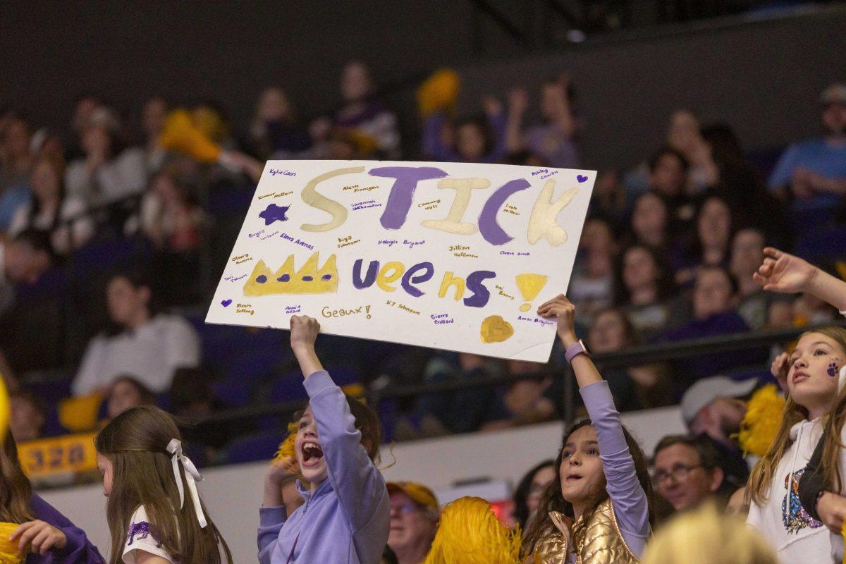 LSU gymnastics fans hold up a "STICK queens!" poster Friday, Feb. 16, 2024, during LSU's win 198.300-197.10 against Auburn in the Pete Maravich Assembly Center.