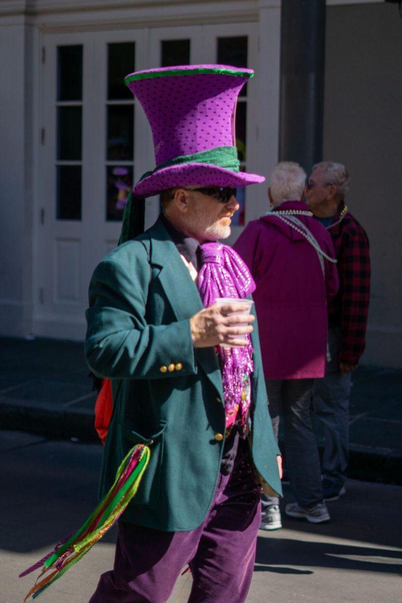 A regal man stands holding a cup Tuesday, Feb. 13, 2024, on Bourbon Street in New Orleans, La.