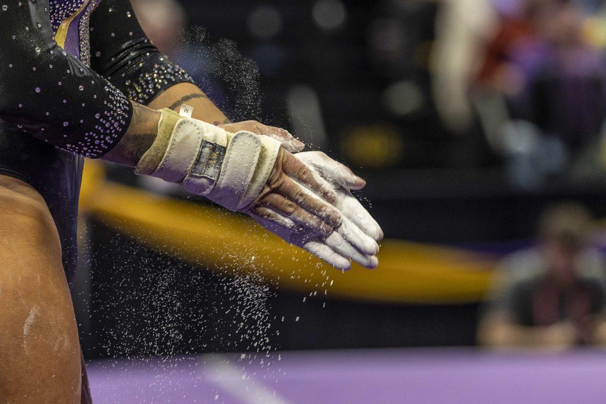 LSU gymnastics junior all-around KJ Johnson chalks her hands Friday, Feb. 16, 2024, during LSU's win 198.300-197.10 against Auburn in the Pete Maravich Assembly Center.