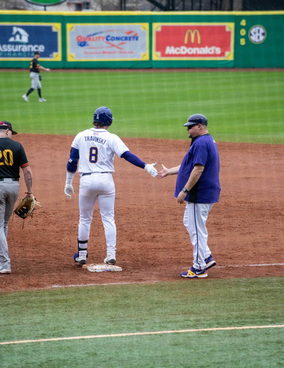 LSU baseball graduate student catcher Hayden Travinski (8) high fives the first base coach during LSU's 11-8 win against VMI on Friday, Feb. 16, 2024, at Alex Box Stadium in Baton Rouge, La.