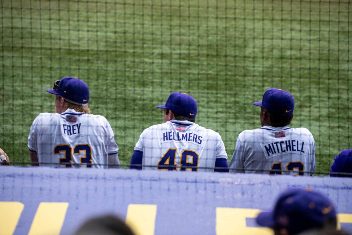 LSU baseball sophomore outfielder Ethan Frey (33), senior pitcher Will Hellmers (48), and freshman outfielder Derrick Mitchell (43) watch the game from the dugout during LSU's 11-8 win against VMI on Friday, Feb. 16, 2024, at Alex Box Stadium in Baton Rouge, La.