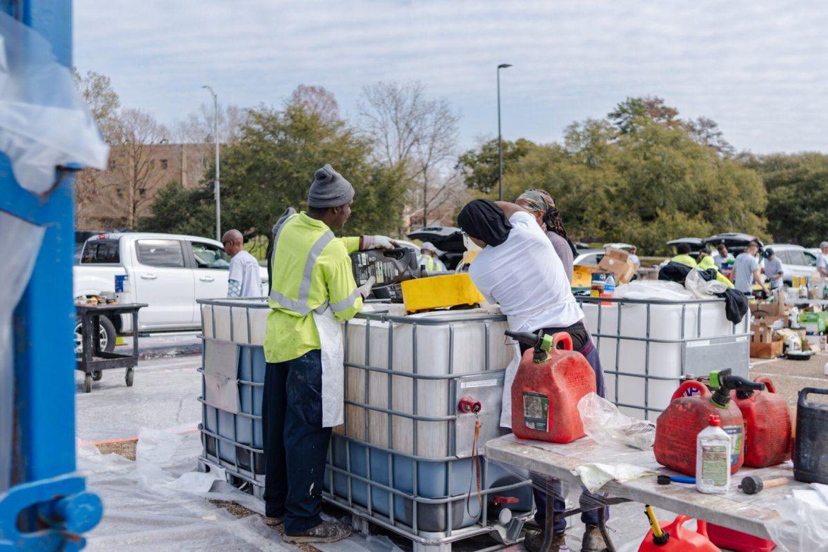 Workers pour liquids into a large container Saturday, March 2, 2024, at the Household Hazardous Materials Collection Day on LSU's campus in Baton Rouge, La.