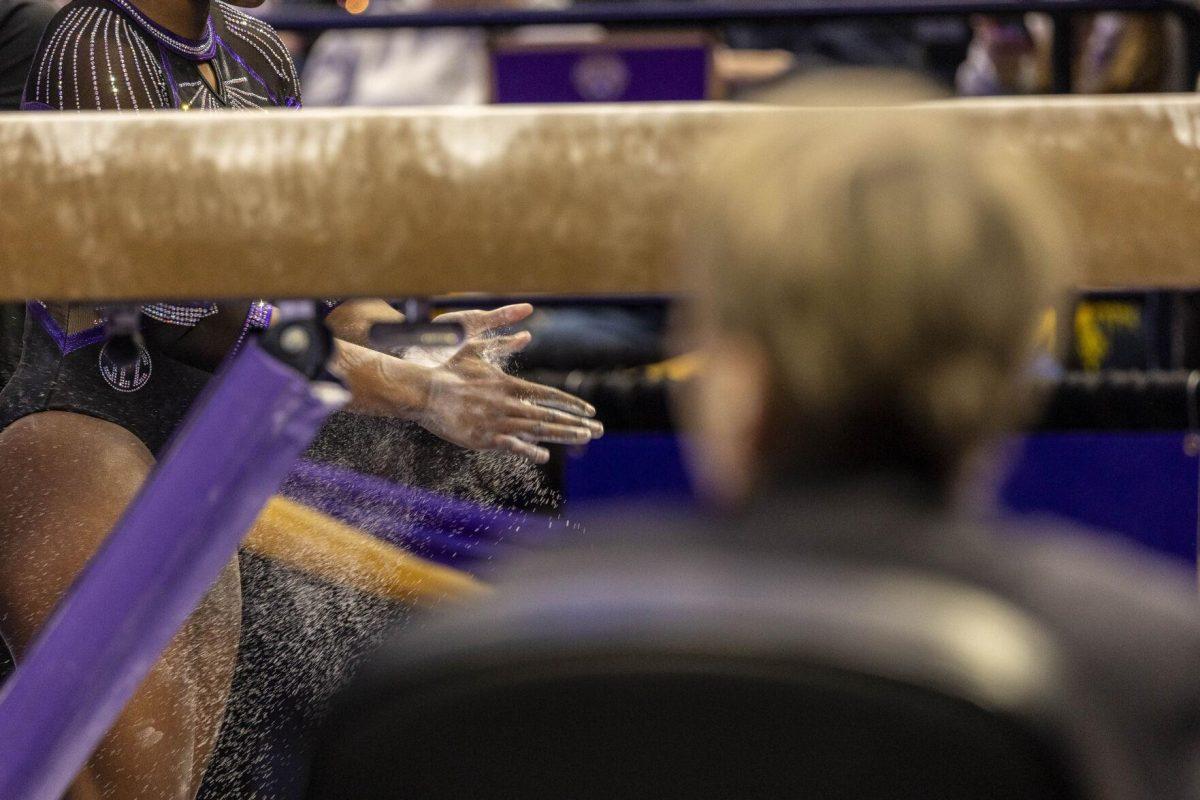 LSU gymnastics graduate student all-around Kiya Johnson chalks her hands Friday, March 1, 2024, during LSU's 198.325-197.325 win over Alabama in the Pete Maravich Assembly Center.