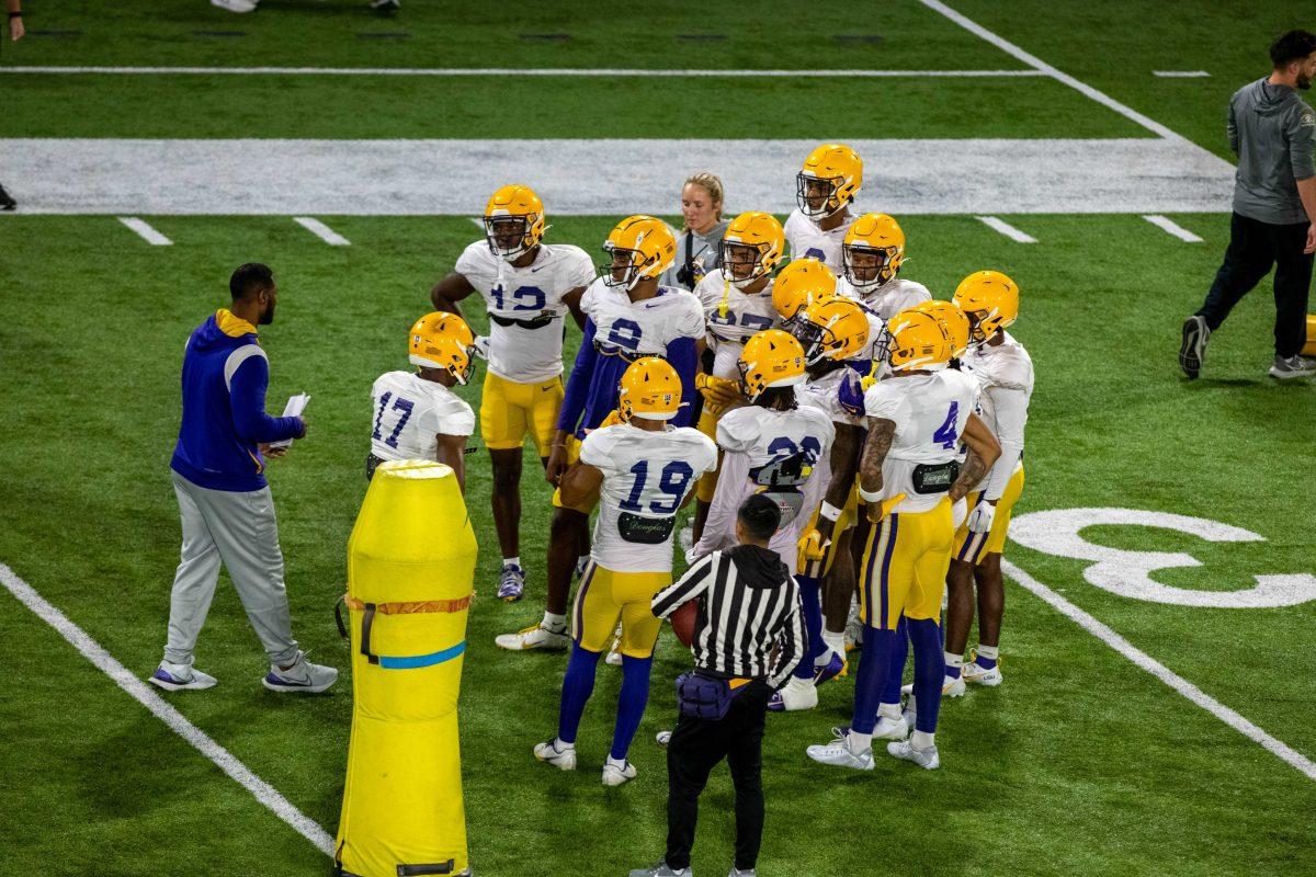 A coach talks to a group of LSU football players during practice on Wednesday, March 20, 2024, at the indoor practice facility in Baton Rouge, La.