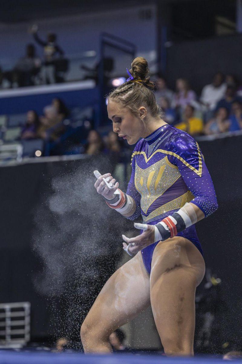 LSU gymnastics graduate student all-around Savannah Schoenherr blows excess chalk off her hands Saturday, March 23, 2024, during LSU's 198.075 victory in the 2024 SEC Gymnastics Championship in the Smoothie King Center in New Orleans, La.