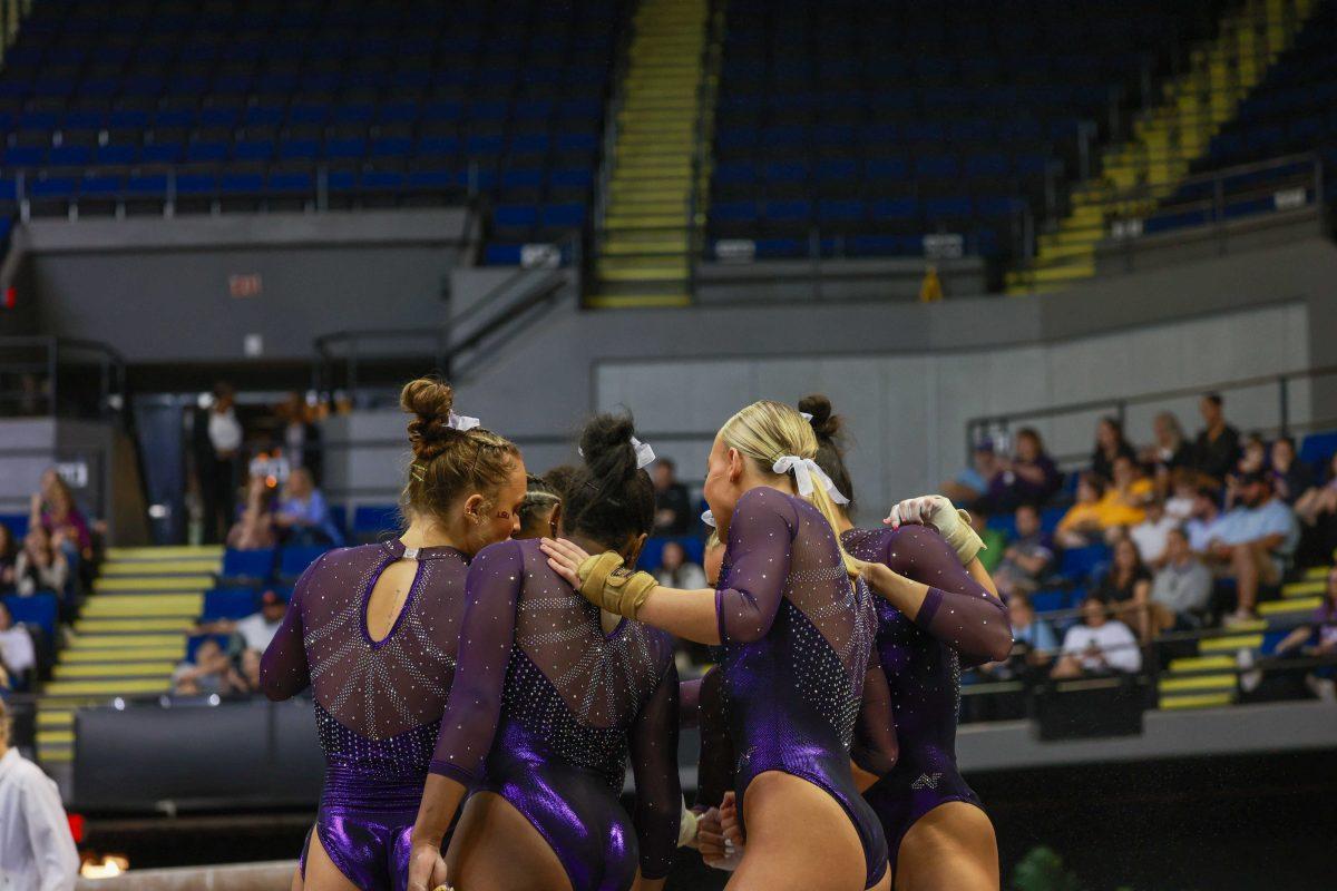 The team LSU gymnastics team huddles up Friday March 8, 2024, during the Podium Challenge against Auburn, George Washington, Texas Woman's in the Raising Cane's River Center in Baton Rouge, La.&#160;