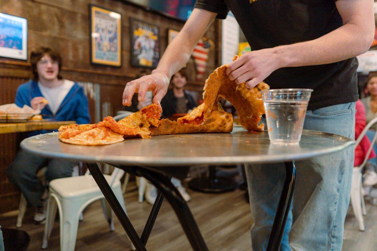 Jacob Chastant tears apart the pizza slice Sunday, Feb. 18, 2024, at Fat Boy's Pizza on Nicholson Drive in Baton Rouge, La.