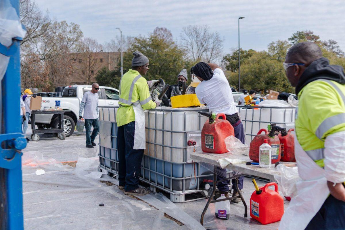 Workers pour liquids into a large container Saturday, March 2, 2024, at the Household Hazardous Materials Collection Day on LSU's campus in Baton Rouge, La.