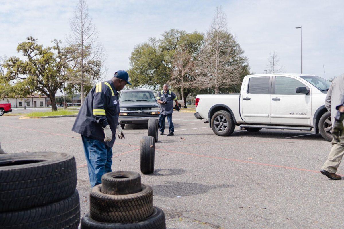 Workers roll tires to stack in piles Saturday, March 2, 2024, at the Household Hazardous Materials Collection Day on LSU's campus in Baton Rouge, La.