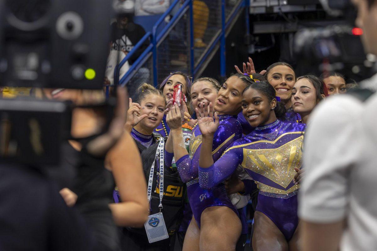The LSU gymnastics team attempts to distract viewers during head coach Jay Clark's interview Saturday, March 23, 2024, during LSU's 198.075 victory in the 2024 SEC Gymnastics Championship in the Smoothie King Center in New Orleans, La.