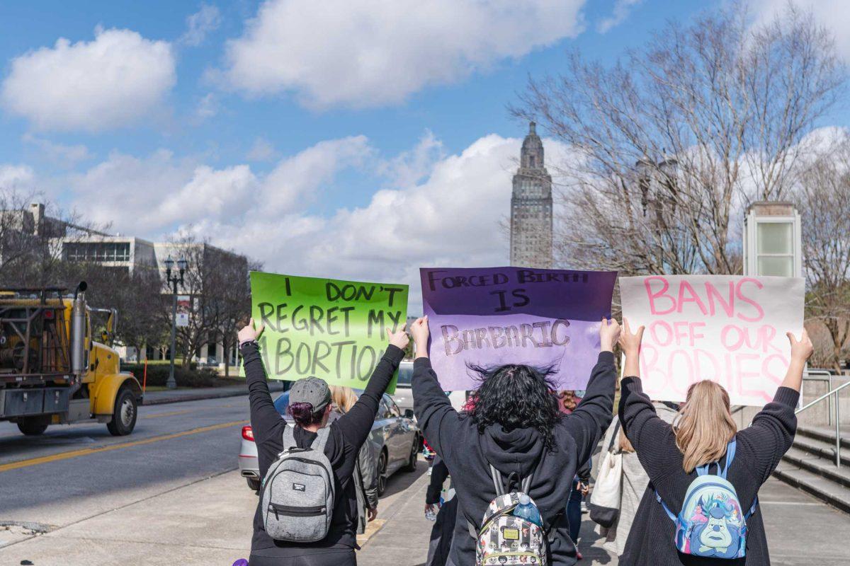 A trio carries signs on Sunday, Jan. 22, 2023, during an abortion rights march in downtown Baton Rouge, La.