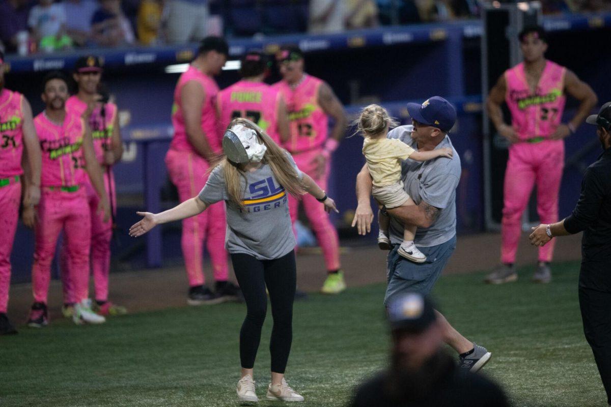 A man throws a pie at his wife's face with his daughter after a friendly competition Thursday, March 14, 2024, during the Savannah Bananas 5-4 loss to the Party Animals during their world tour stop at Alex Box Stadium in Baton Rouge, La.