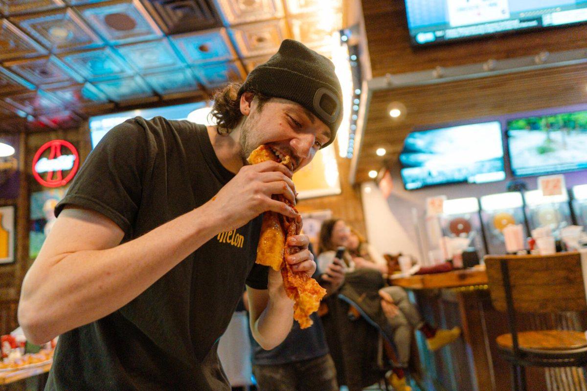 Jacob Chastant tears into the pizza slice with his teeth Sunday, Feb. 18, 2024, at Fat Boy's Pizza on Nicholson Drive in Baton Rouge, La.