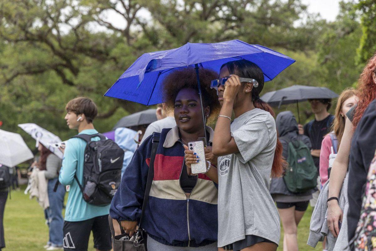 LSU students duck under an umbrella Monday, April 8, 2024, in anticipation of seeing the 2024 Solar Eclipse on the LSU Parade Ground.