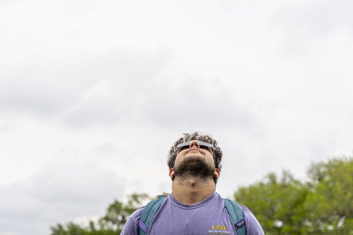 A LSU student looks up into the sky with his solar eclipse glasses Monday, April 8, 2024, in anticipation of seeing the 2024 Solar Eclipse on the LSU Parade Ground.