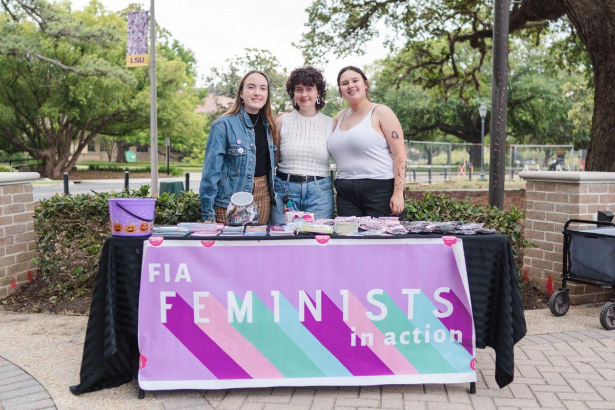 LSU political communications junior Layla Harmon, history senior Lauren Pete and pyschology sophomore Lilli Sims work the Feminists in Action table Wednesday, April 24, 2024, during a Denim Day event at the LSU amphitheater.