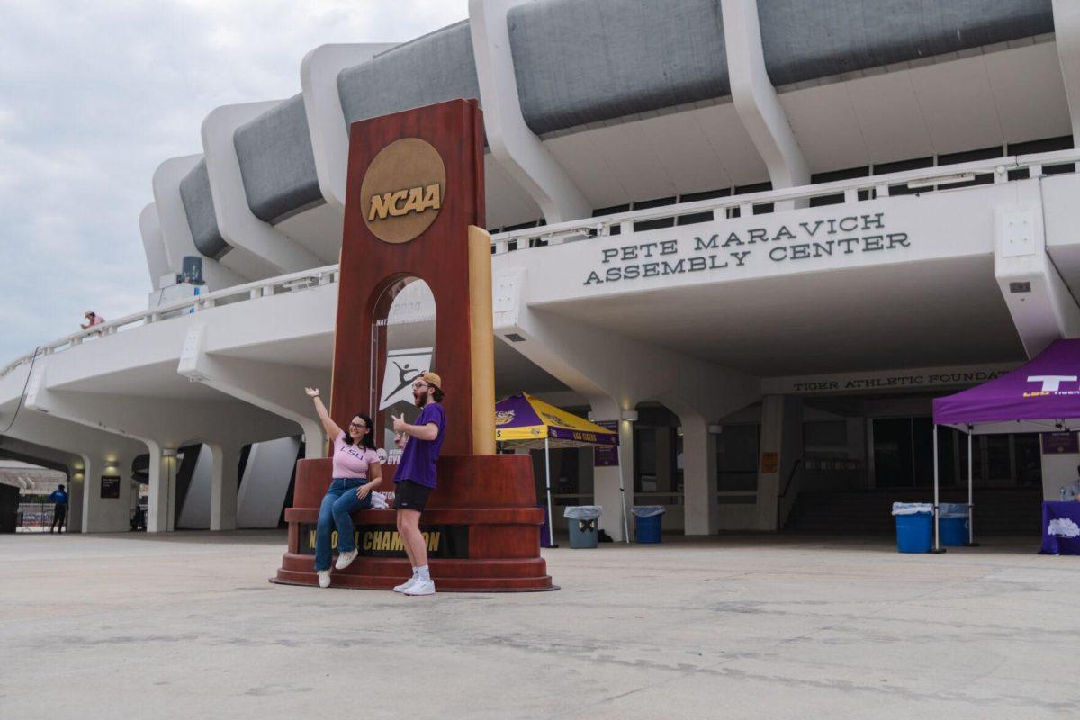 A duo poses with a giant trophy Wednesday, April 24, 2024, at the LSU gymnastics championship parade on LSU's campus in Baton Rouge, La.