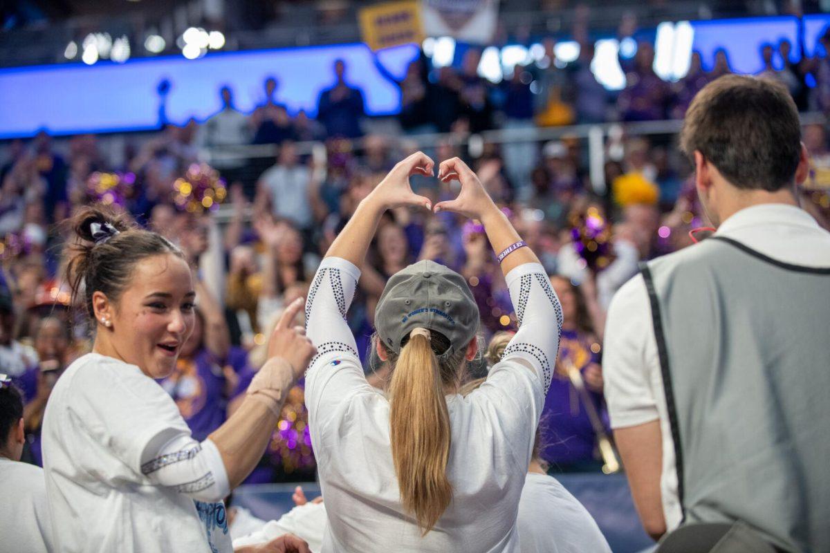 LSU gymnastics team member holds up a heart for the crowd of LSU fans following LSU's NCAA Championship win on Saturday, April 20, 2024, in Fort Worth, Tx.