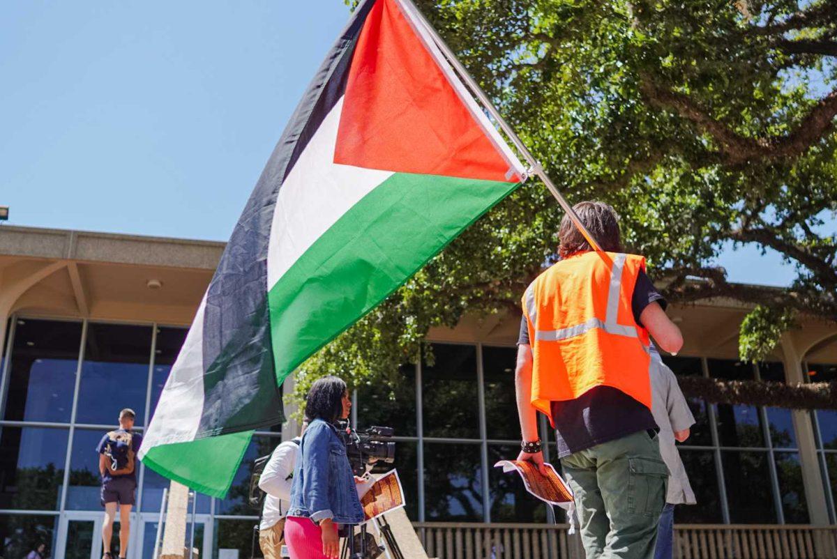 A student holds a Palestinian flag Thursday, April 25, 2024, during the Die-in for Gaza on LSU&#8217;s campus in Baton Rouge, La.