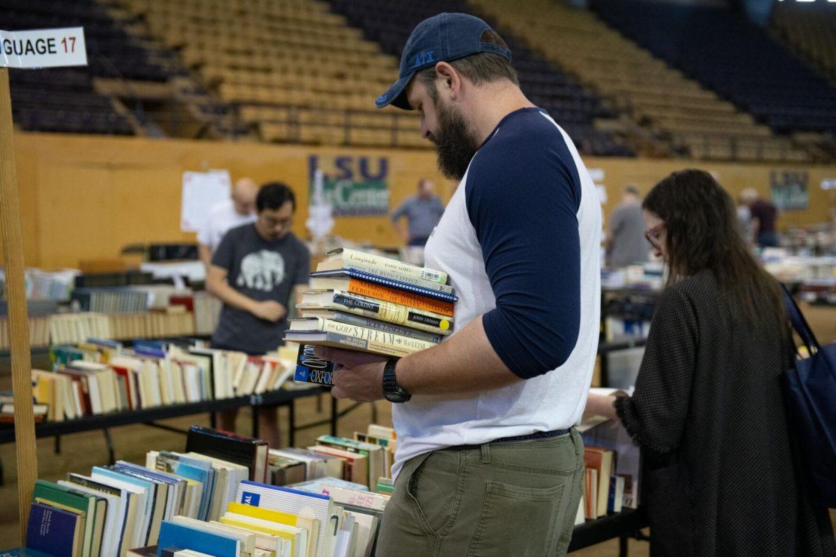 An attendee holds a stack of books Sunday, April 14, 2024, during the Friends of the LSU Libraries Book Bazaar at the John M. Parker Agricultural Coliseum in Baton Rouge, La.