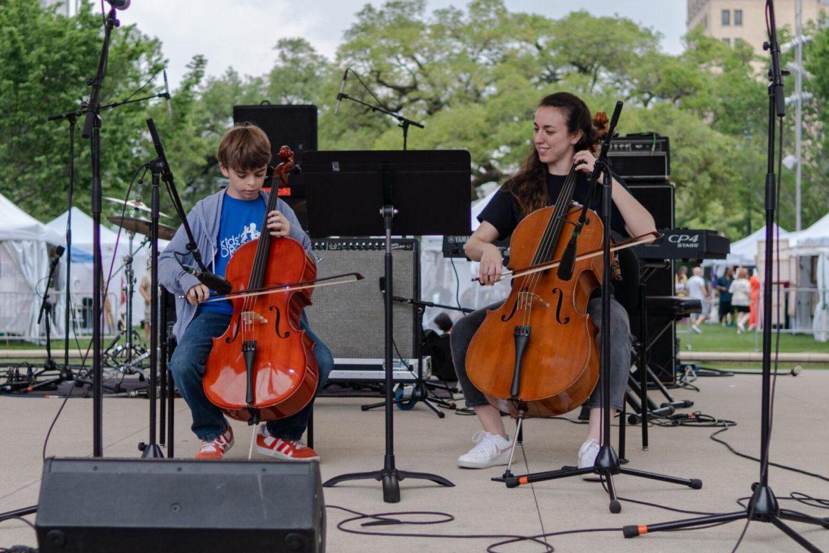 A member of the Kids' Orchestra performs with helper Saturday, April 20, 2024, at the Baton Rouge Blues Festival.