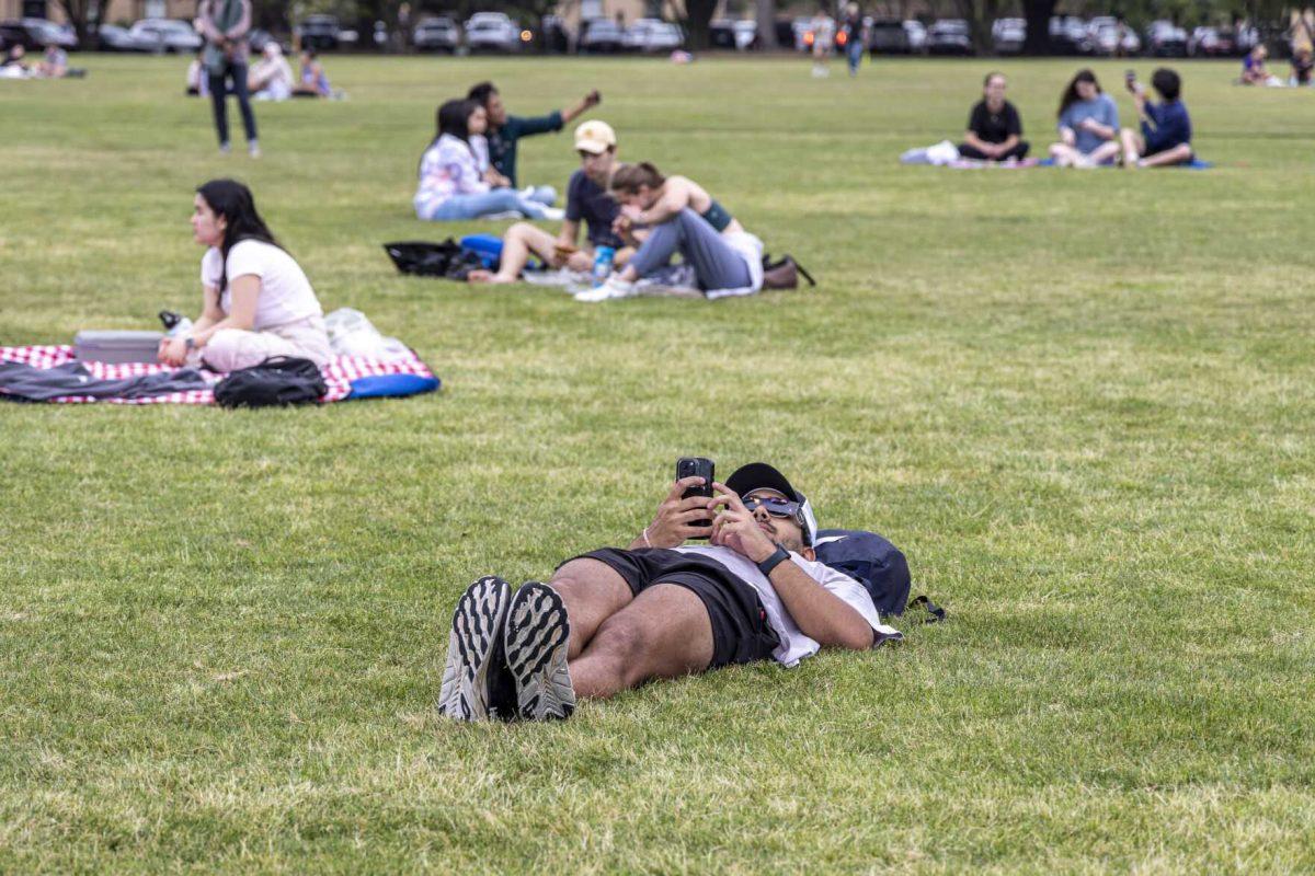 A student scrolls through his phone Monday, April 8, 2024, in anticipation of seeing the 2024 Solar Eclipse on the LSU Parade Ground.
