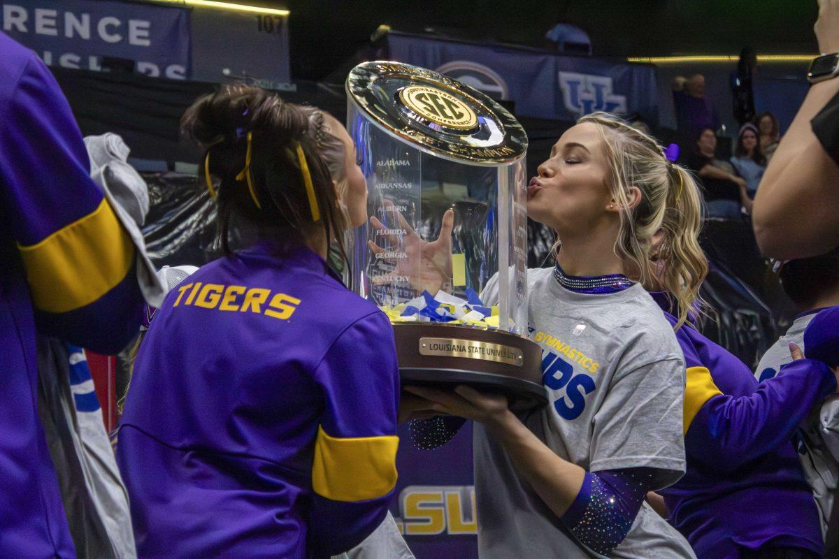 LSU gymnastics junior all-around KJ Johnson (left) and senior all-around Olivia Dunne (right) kiss the SEC Championship trophy Saturday, March 23, 2024, following LSU's 198.075 victory in the 2024 SEC Gymnastics Championship in the Smoothie King Center in New Orleans, La.