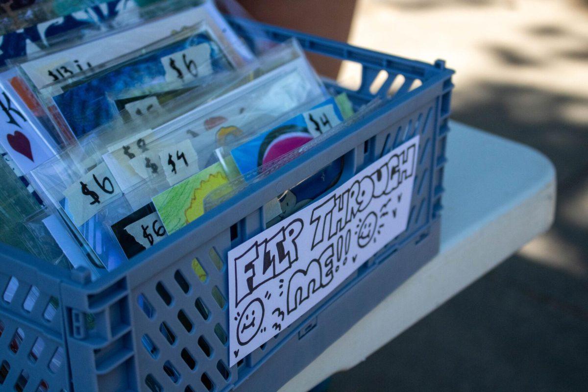 The sign reads 'flip through me' at the art sale on Wednesday, April 24, 2024, in Free Speech Alley on LSU's campus.