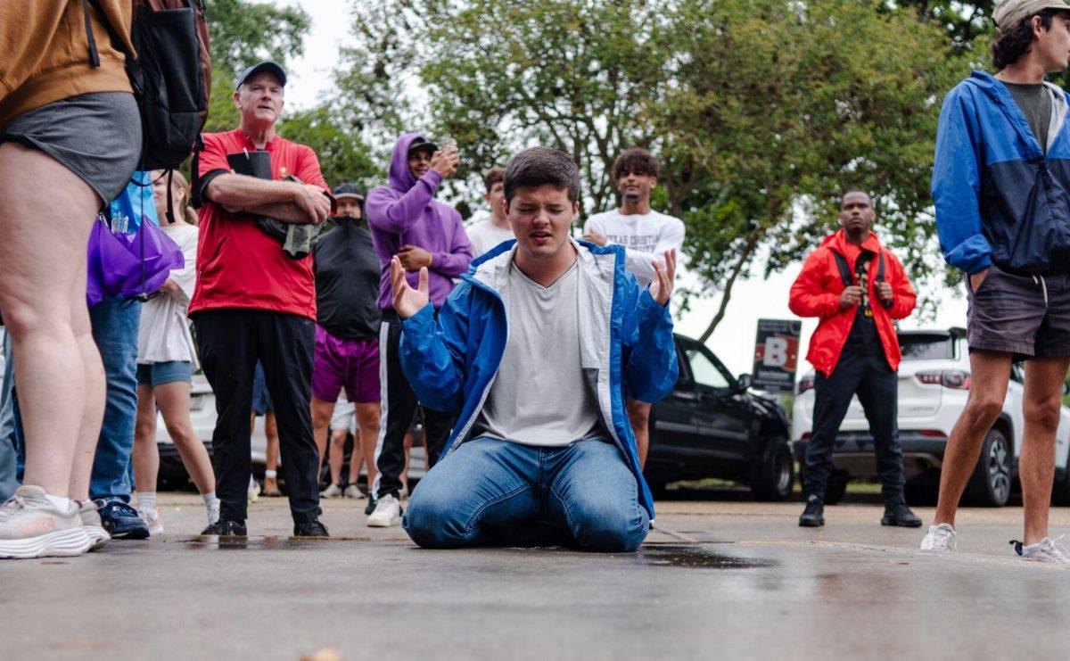 A counter-protester kneels on the sidewalk Friday, May 3, 2024, in Free Speech Alley on LSU's campus in Baton Rouge, La.