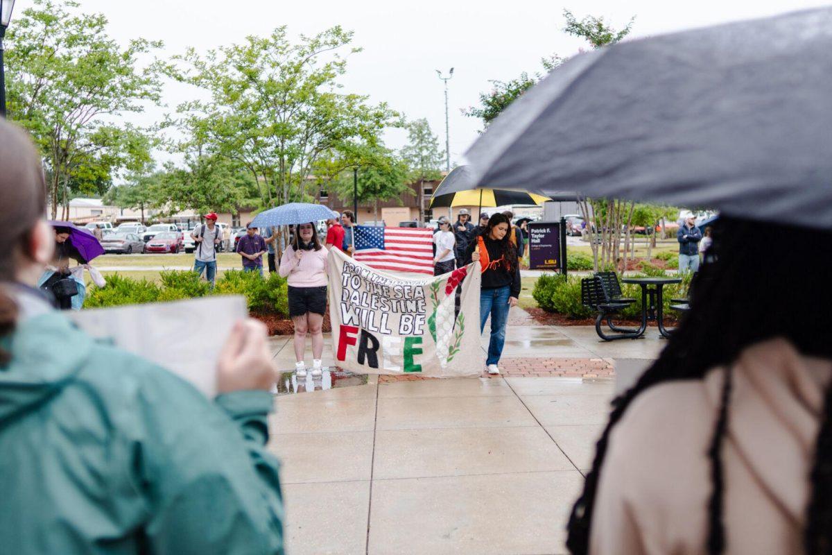 Pro-Palestinian protesters hold a banner reading "From the river to the sea Palestine will be free" while counter-protesters hold an American flag Friday, May 3, 2024, outside of Patrick F. Taylor Hall on LSU's campus in Baton Rouge, La.