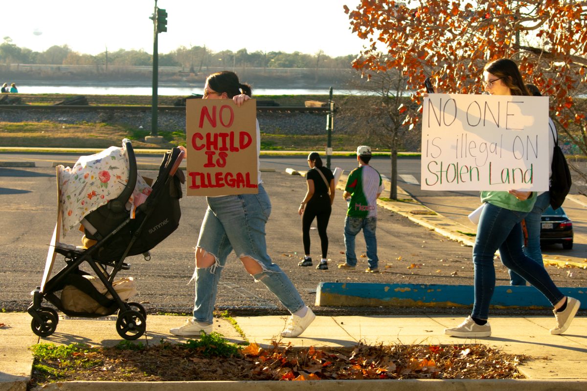 A family gathers to protest, holding signs against mass deportation Sunday, Feb. 2, 2025, at Convention Street and River Road in downtown Baton Rouge, La.