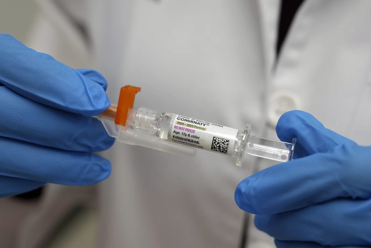 A pharmacist holds a COVID-19 vaccine at a pharmacy in New York, Tuesday, Sept. 24, 2024.