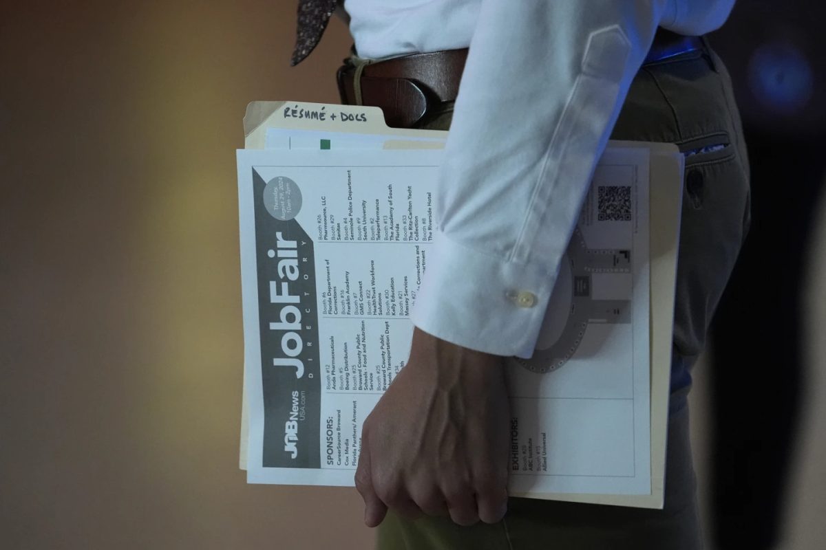 A person waits in line for a prospective employer at a job fair, Thursday, Aug. 29, 2024, in Sunrise, Fla.