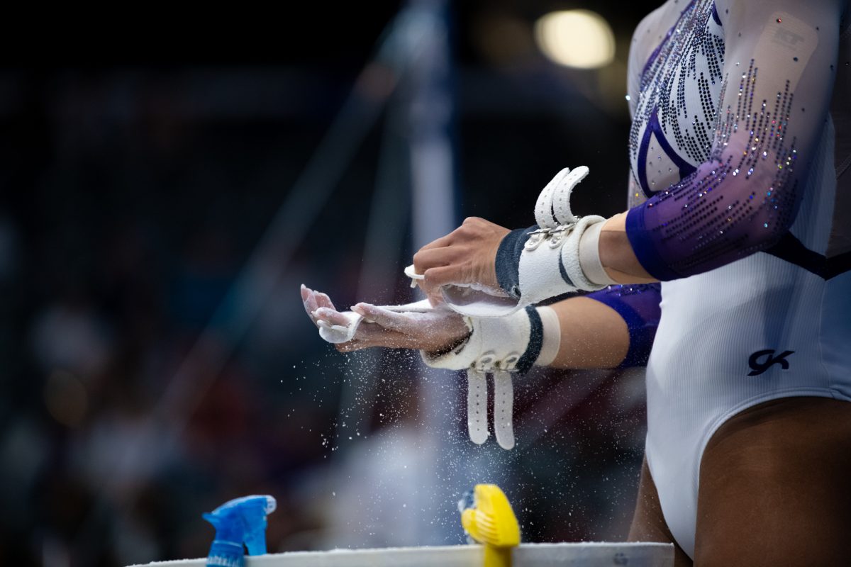 An LSU gymnast puts chalk on her grips before bars during LSU's SEC Championship win on Saturday, March 22, 2025, at the Legacy Arena in Birmingham, Al.