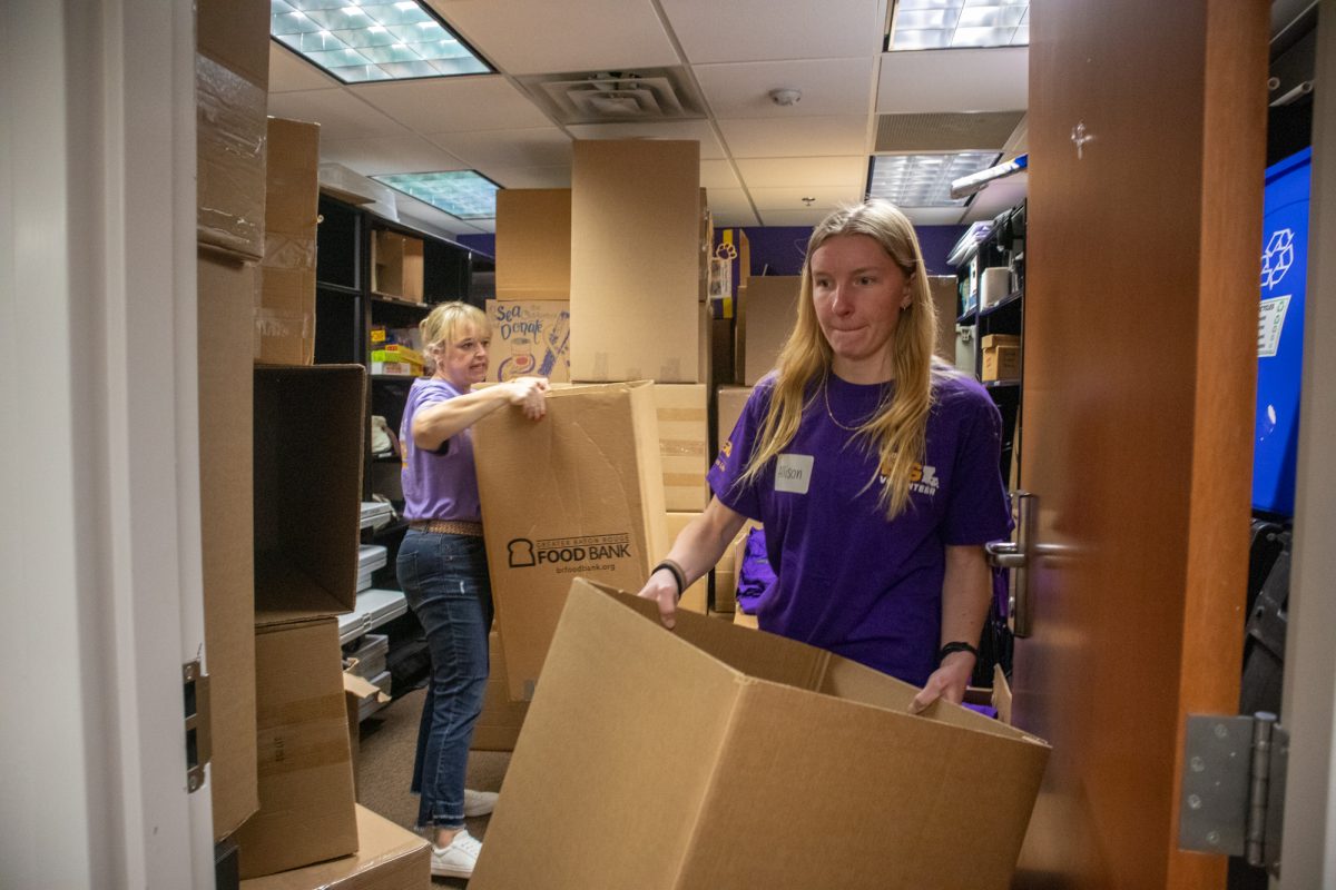 Geaux Big staff and a volunteer take food bank boxes out of the closet to decorate Tuesday, March 11, 2025, in the Campus Life Office in Baton Rouge, La.