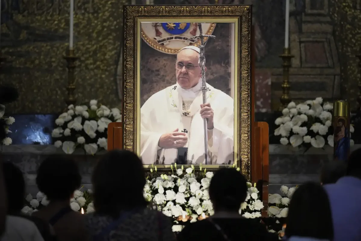 Catholics light candles in front of a portrait of the late Pope Francis at the Manila, Philippines Tuesday, April 22, 2025.  