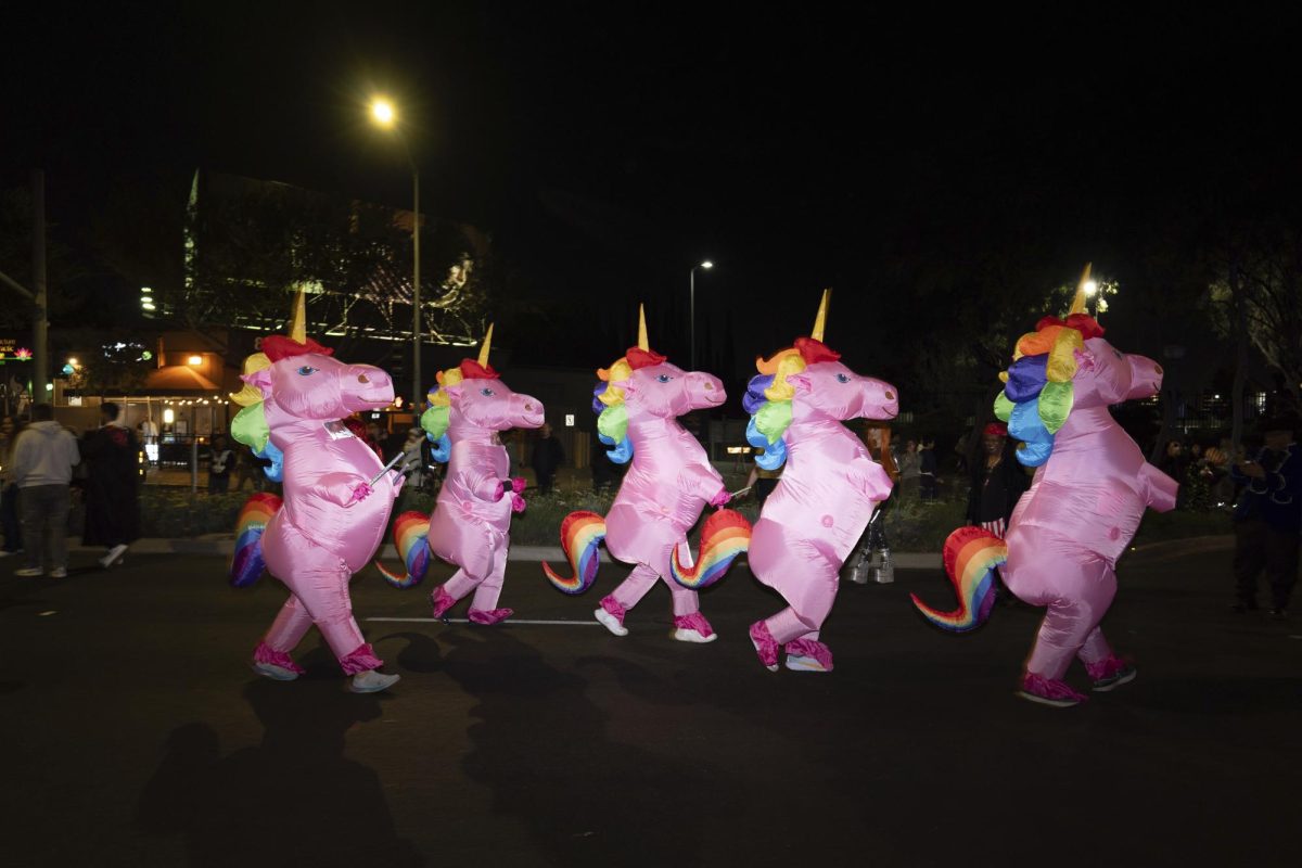 People in unicorn costumes walk along the street during the Halloween Carnival in West Hollywood, Calif., Thursday, Oct. 31, 2024. 