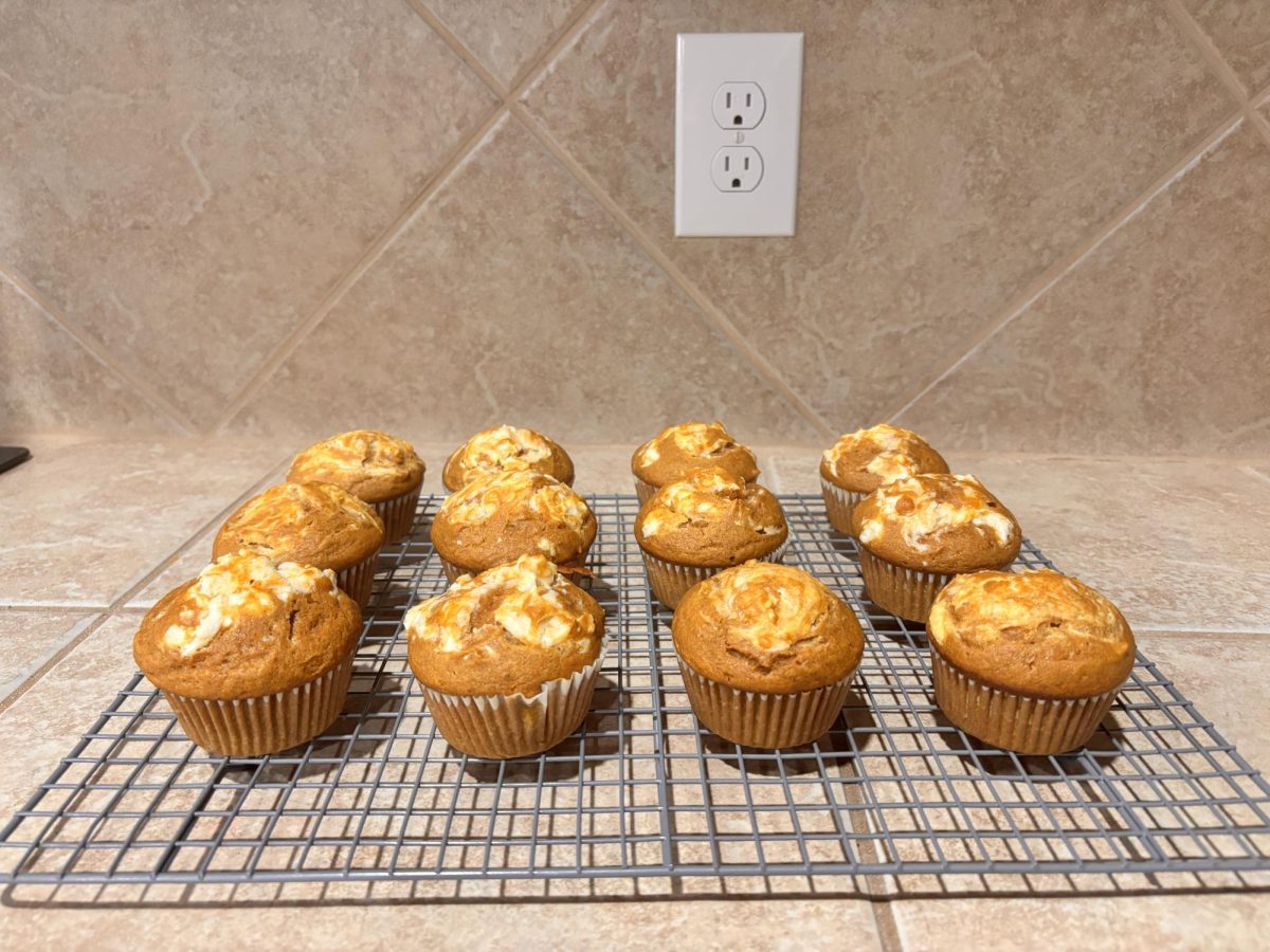 Pumpkin spice cream cheese muffins sit on a baking rack to cool.