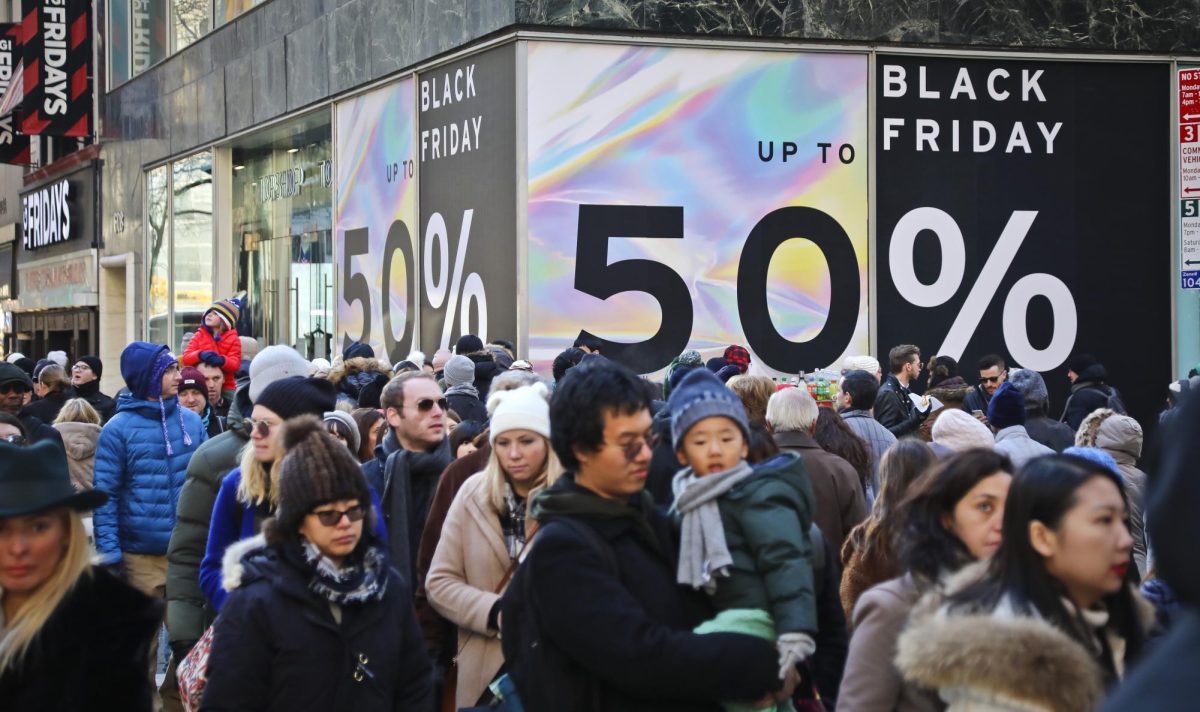 Crowds walk past a large store sign displaying a Black Friday discount in midtown Manhattan, Friday, Nov. 23, 2018, in New York. (AP Photo/Bebeto Matthews, File)
