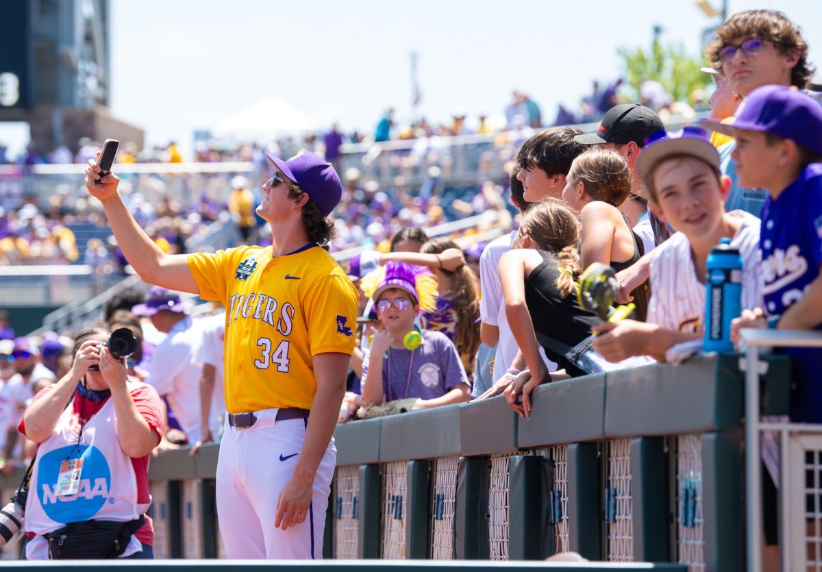 LSU baseball redshirt sophomore right-handed pitcher Chase Shores (34) takes a selfie with fans before LSU’s 5-3 win over Coastal Carolina in the Men’s College World Series Championship Sunday, June 22, 2025, at Charles Schwab Field in Omaha, Ne.