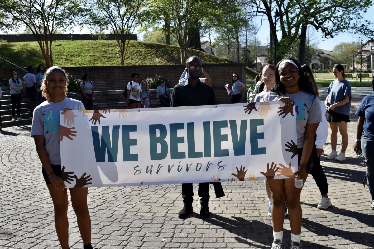 Two students hold a banner for the 2nd annual Believe March in front of Cyprus Hall on Tuesday, March 25, 2025.