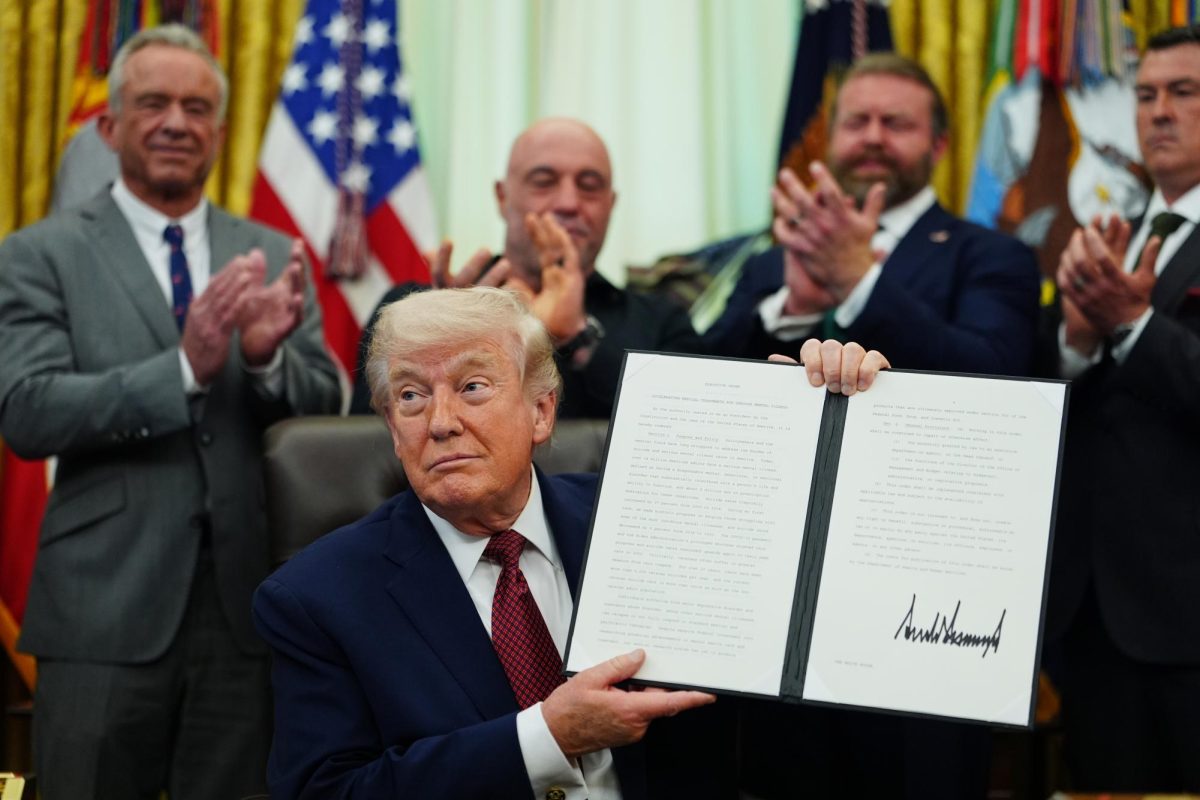 President Donald Trump holds up a signed executive order in the Oval Office of the White House, Saturday, April 18, 2026, in Washington.
