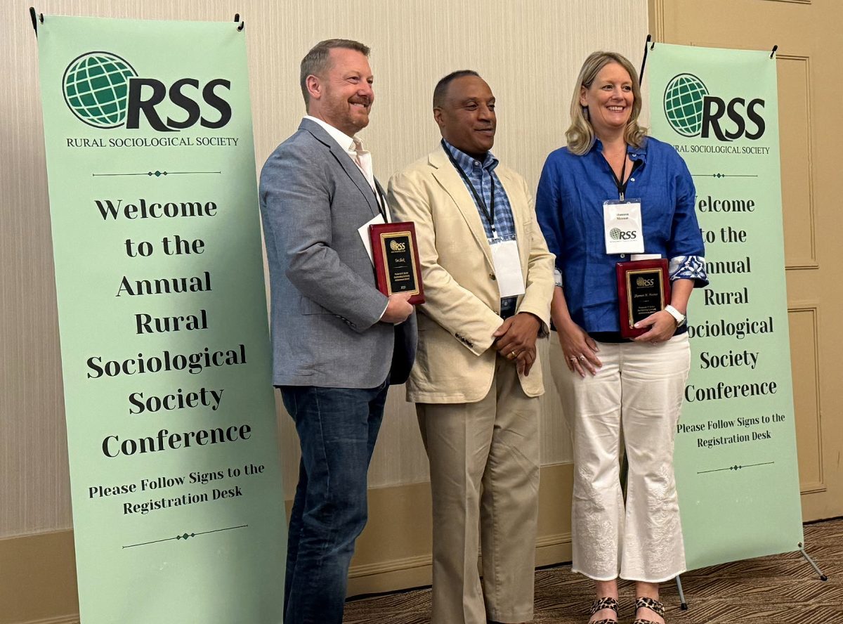 Tim Slack and Shannon Monnat stand with former RSS President Ken Robinson to accept the 2025 Frederick H. Buttel Outstanding Scholarly Achievement Award for their book Rural and Small-Town America: Context, Composition, and Complexities.